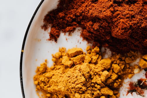 Free Top view of small heaps of ground chili and curcuma powders in metal bowl on white surface Stock Photo