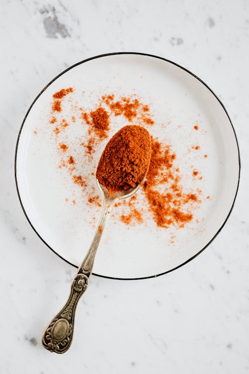Free Top view of metal spoon with ground paprika in metal round bowl on marble desktop Stock Photo