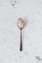 Top view of metal teaspoon with mix of salt and curcuma on smooth marble surface