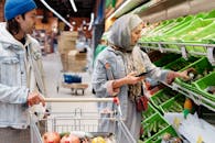 在超市购买蔬菜时，不同的夫妇用智能手机讨论选择