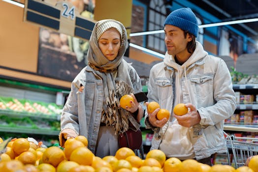 Couple selecting fresh oranges in a supermarket, depicting a modern lifestyle.