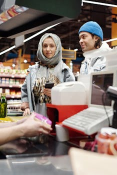 A middle eastern couple at a supermarket checkout engaging with a cashier.