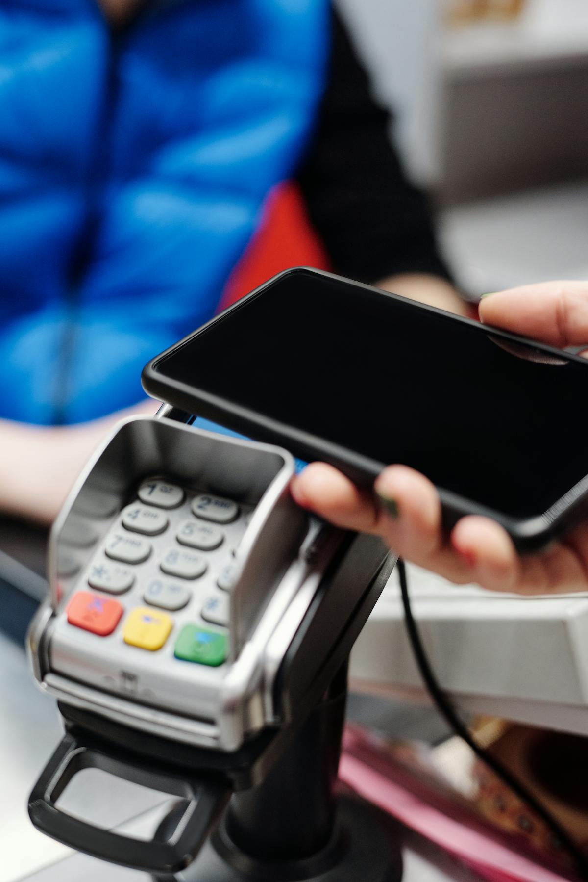 Persona effettua pagamento contactless con smartphone su terminale POS