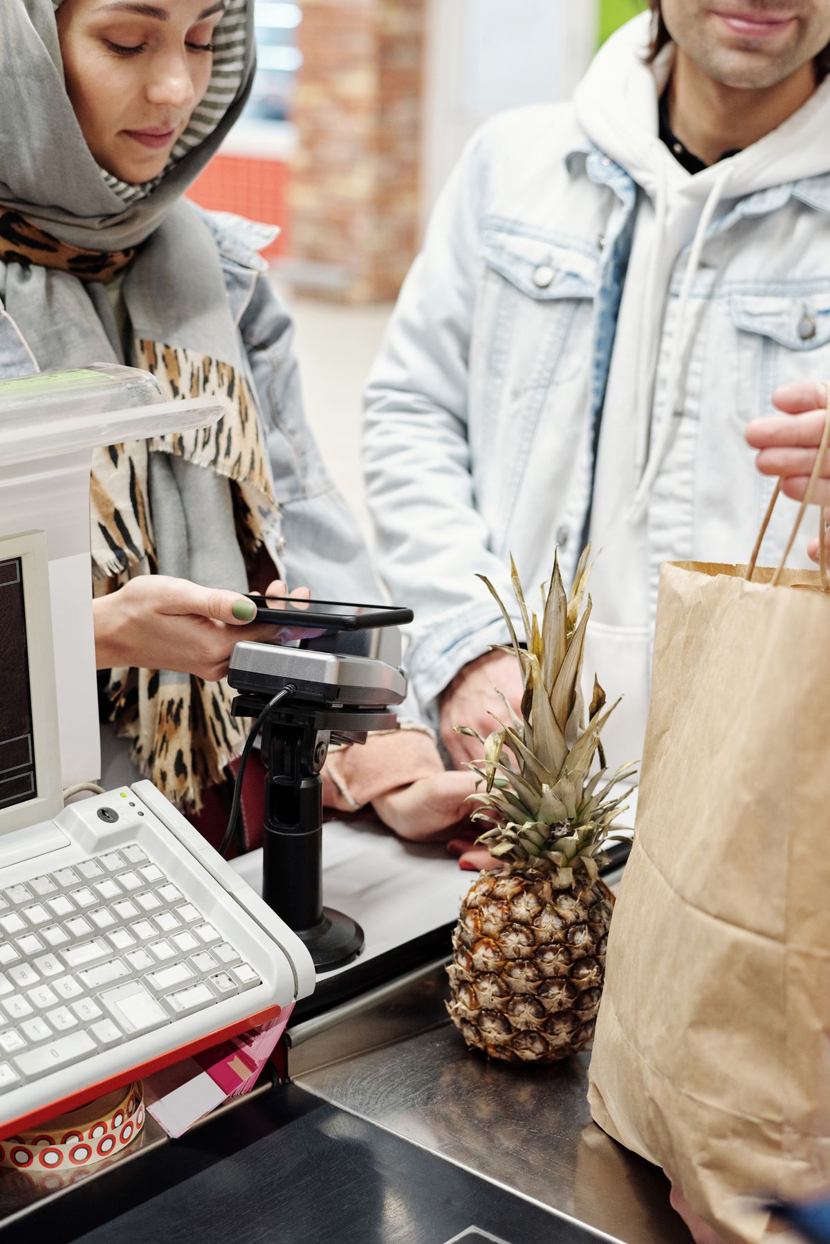 A woman paying for groceries with her smartphone at a checkout counter
