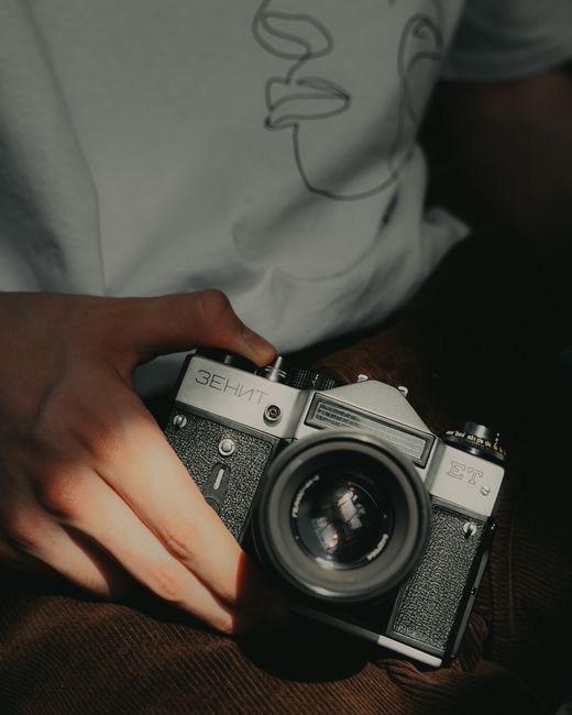 From above of crop unrecognizable person showing old fashioned digital photo camera with lens