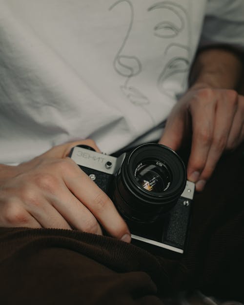 From above of crop anonymous photographer showing vintage reflex photo camera with lens