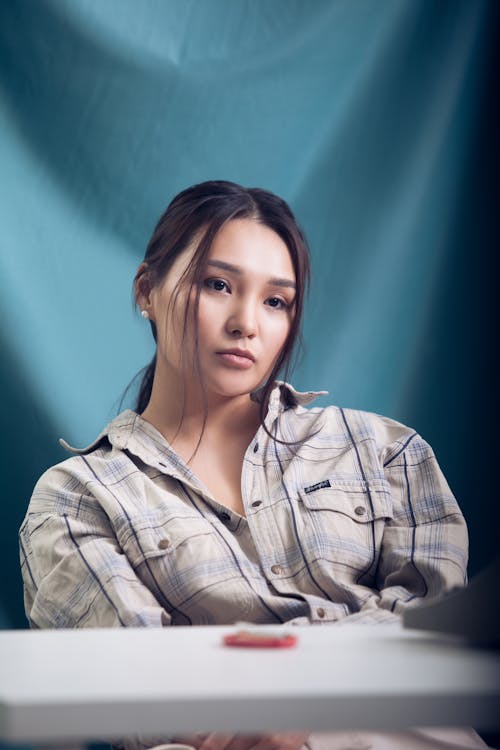 Thoughtful woman sitting near blue curtain