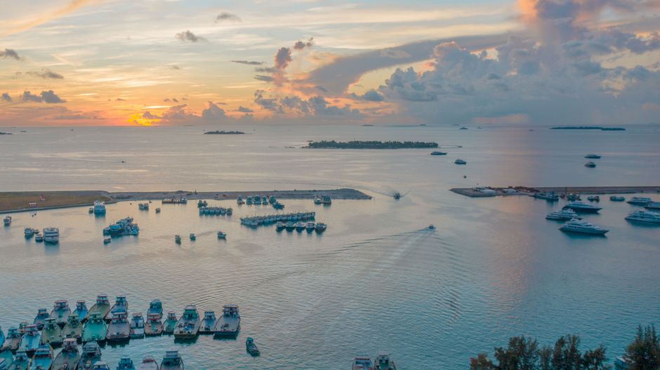 Yachts and boats on calm rippling sea water under evening sky full of fluffy clouds