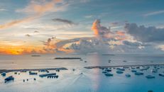 Panorama of calm rippling sea water with boats located under evening sky with white clouds