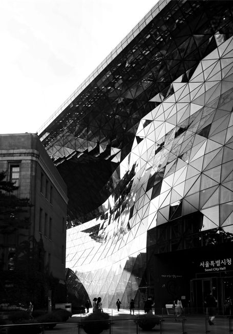 Dramatic black and white image of the glass facade of Seoul City Hall, showcasing modern architecture style.