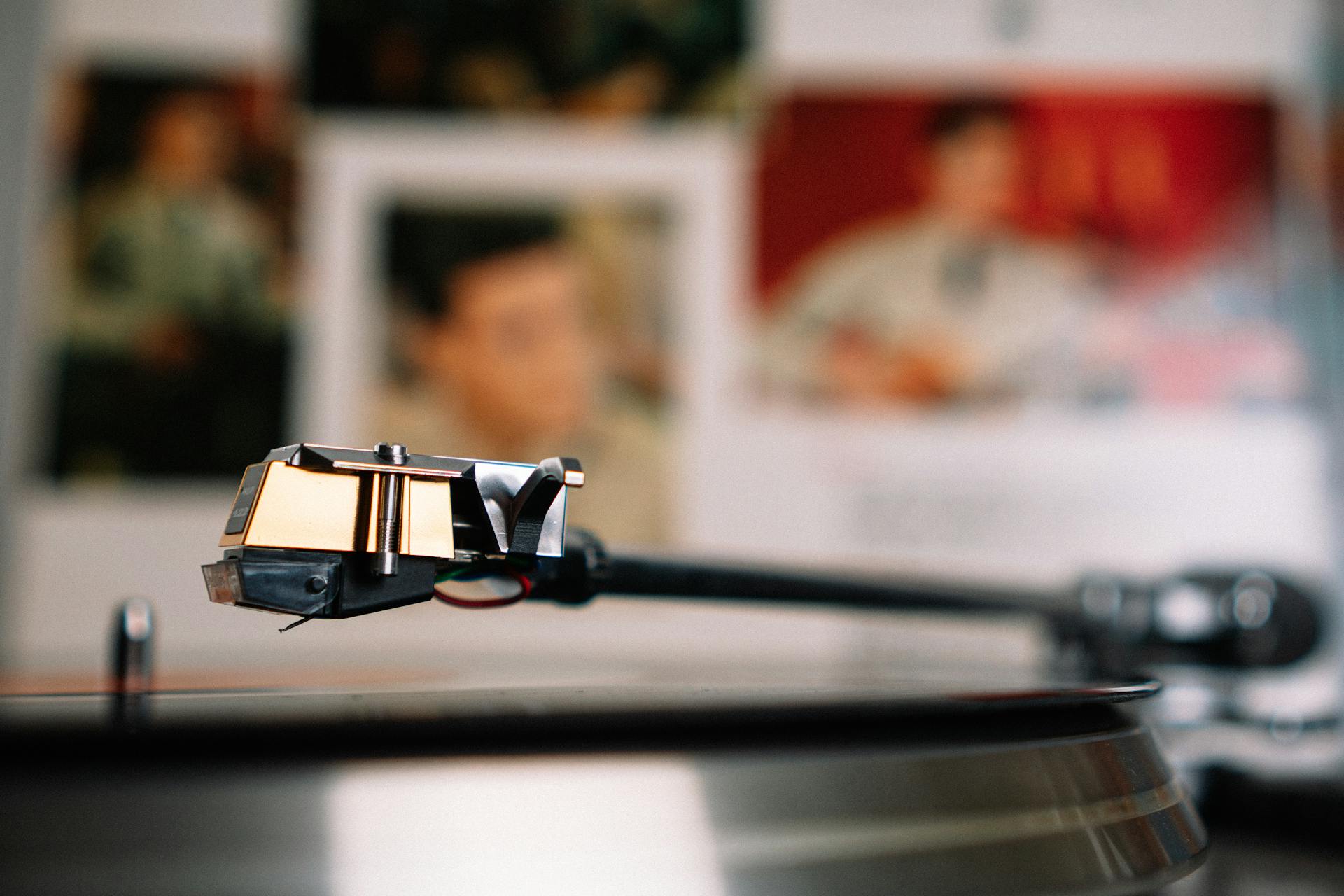 Vintage vinyl record player placed on table against wall with blurred photos of musicians in light living room