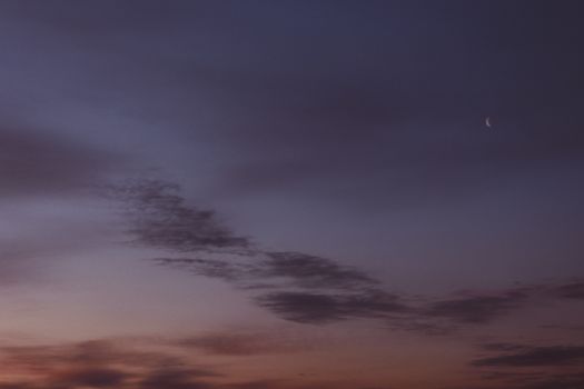 From below wonderful scenery of dark late evening sky with light clouds and new moon