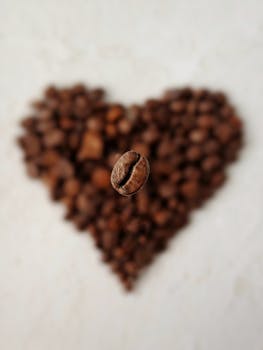 A detailed close-up of a single coffee bean with a heart-shaped background of roasted beans, showcasing coffee artistry.