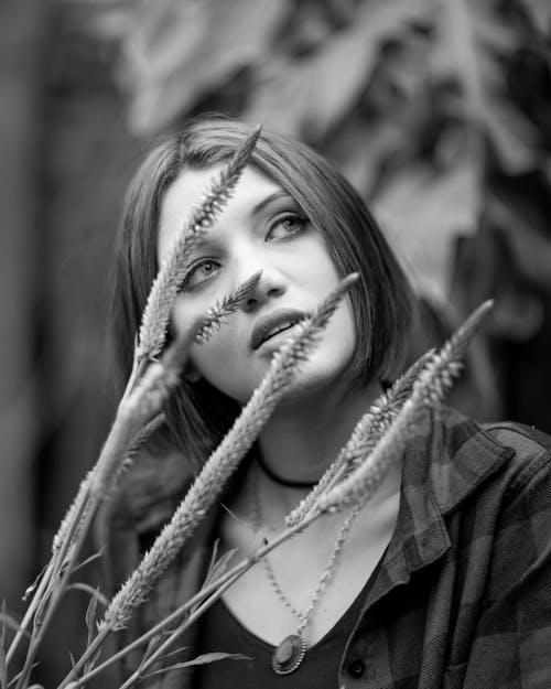 Contemplative woman in nature behind plant stem