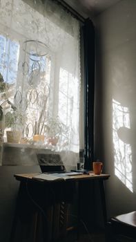 Serene home office with sunlight streaming through a window, highlighting a desk with a coffee cup.