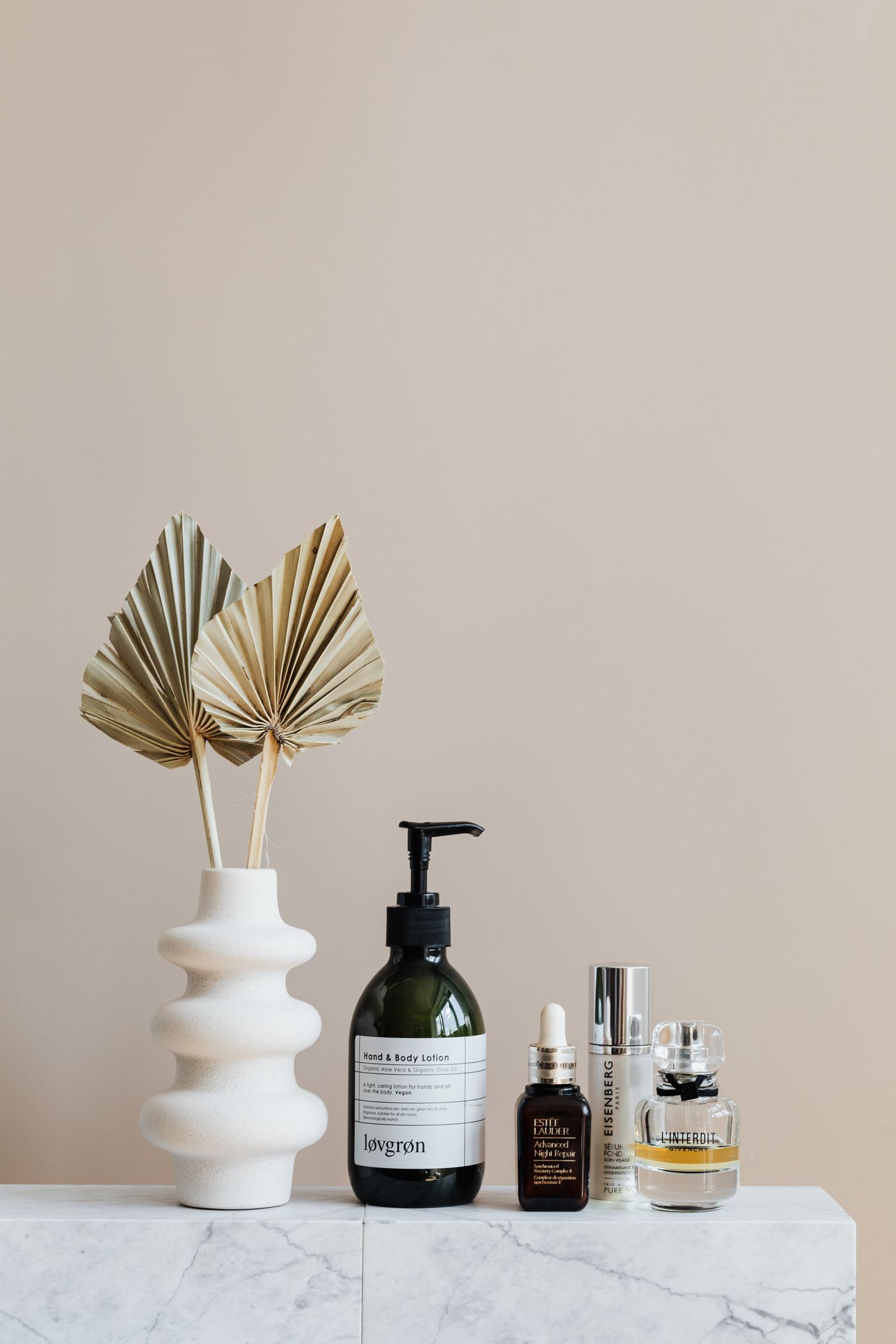 A calm still life of a vase and bottles on a shelf