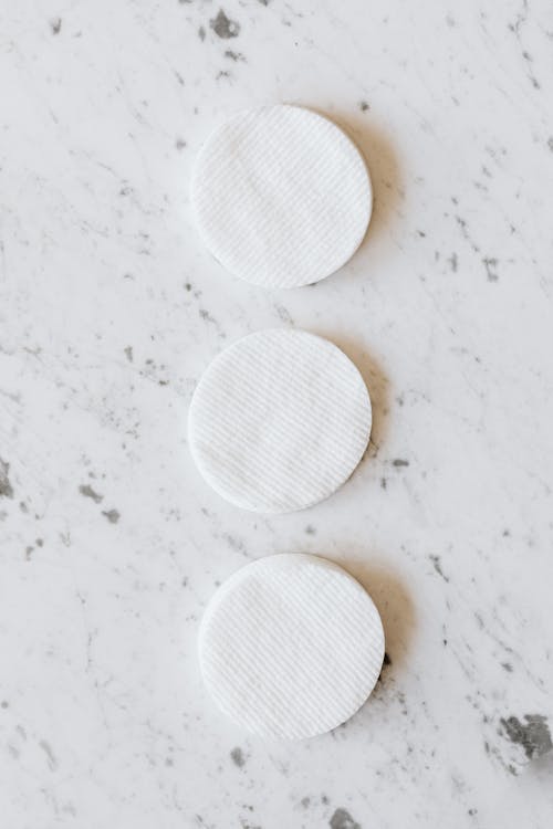 Identical round shaped cotton pads on marble surface