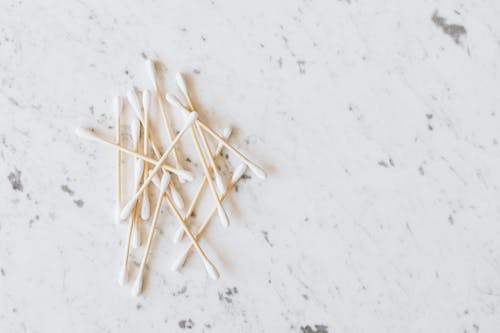 Free From above of heap of similar cotton swabs on thin wooden sticks with soft edges on marble surface with grey lines Stock Photo