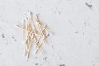 From above of heap of similar cotton swabs on thin wooden sticks with soft edges on marble surface with grey lines