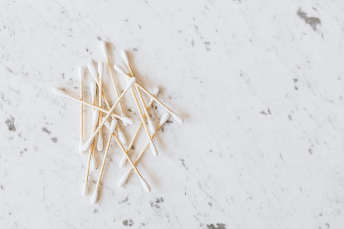 From above of heap of similar cotton swabs on thin wooden sticks with soft edges on marble surface with grey lines