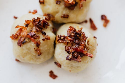 Delicious dumplings with fried bacon slices on plate