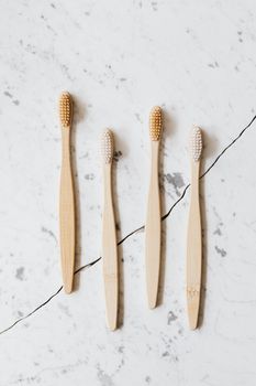 Eco-friendly bamboo toothbrushes arranged neatly on a white marble surface.