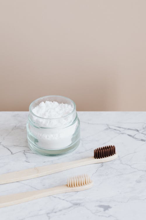 Natural toothpaste in glass jar and wooden toothbrushes