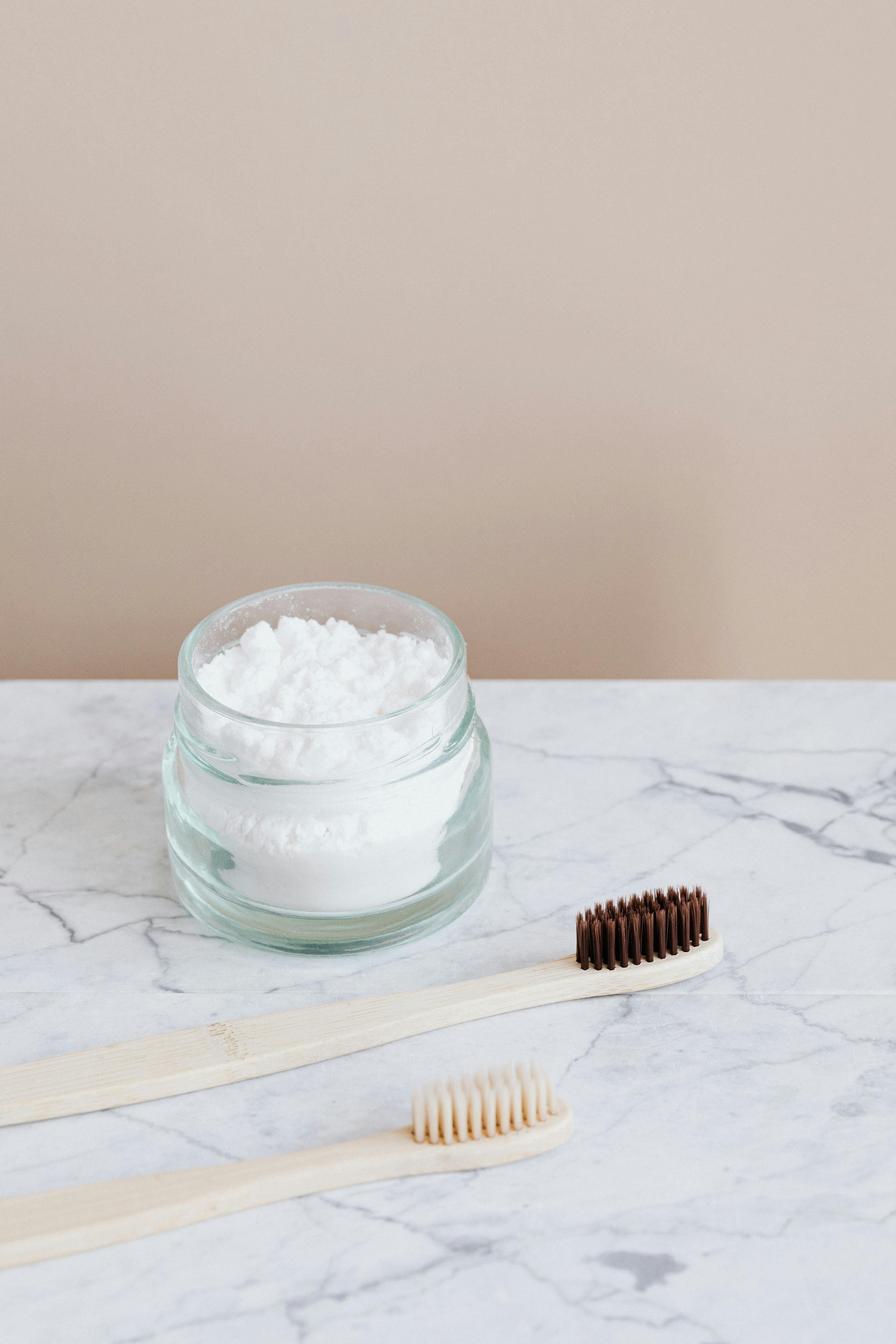 Natural toothpaste in glass jar and wooden toothbrushes · Free Stock Photo