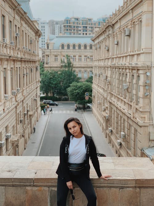 Confident woman leaning on parapet against old city street