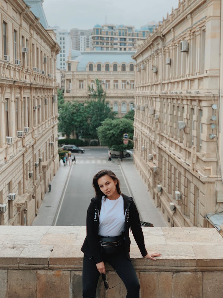 Confident Woman Leaning On Parapet Against Old City Street