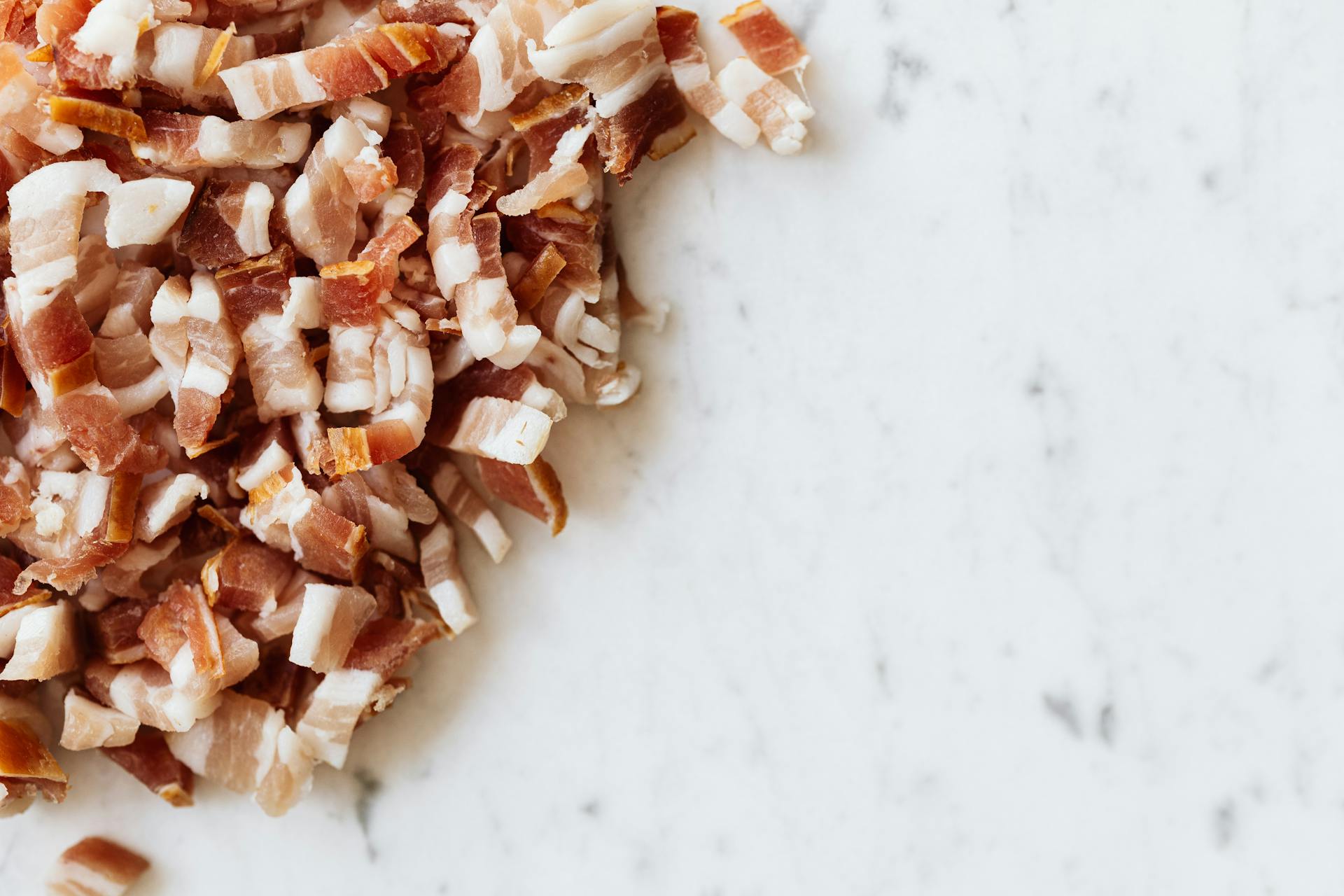 Heap of sliced bacon on marble surface