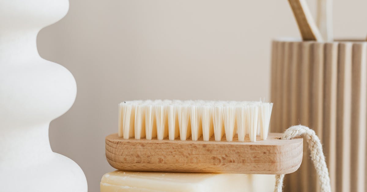 Sustainable consumption concept collection of organic cruelty free soaps with wooden body brush near bamboo sustainable toothbrushes and ceramic white vase on marble tabletop in minimalist bathroom