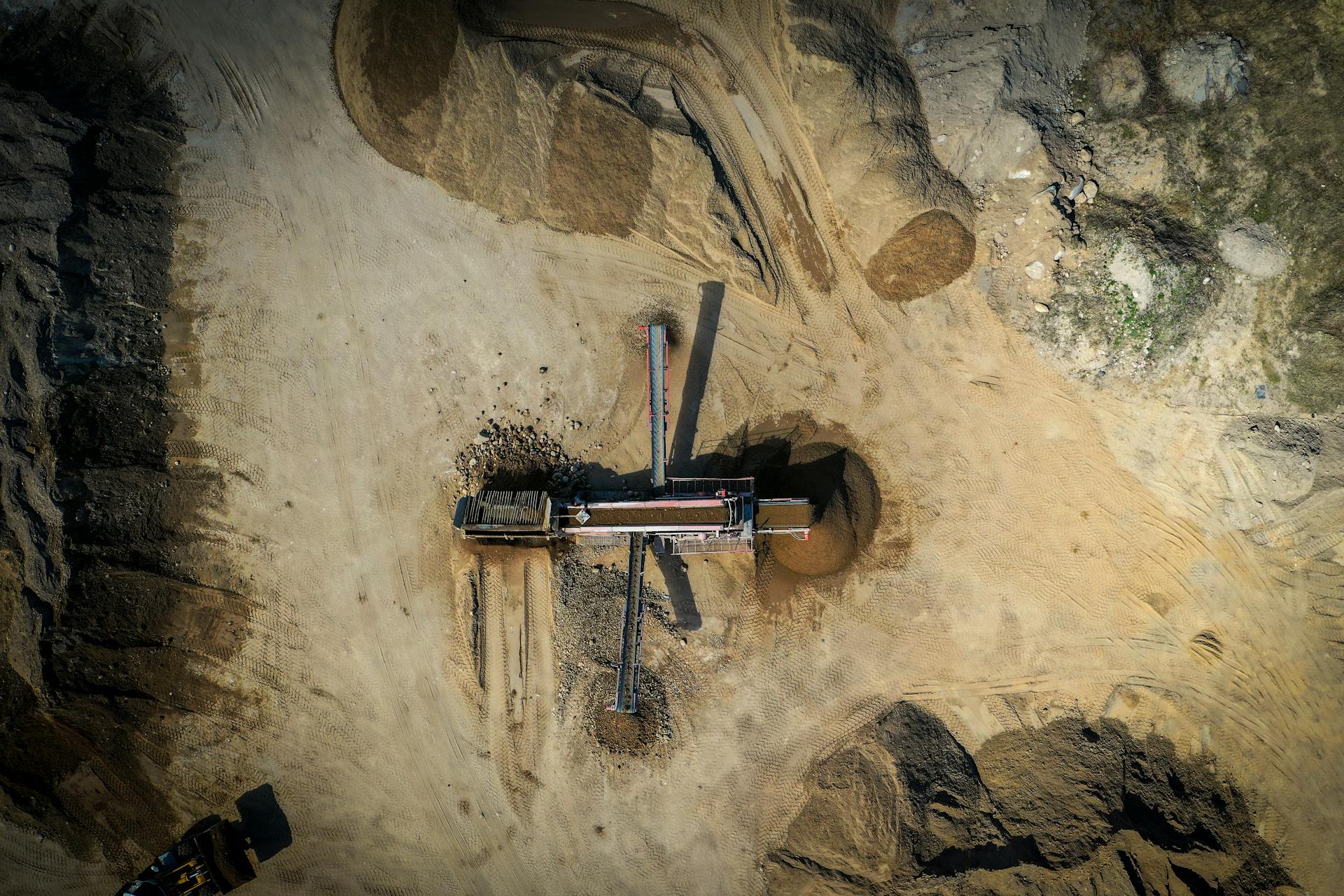 Aerial view of old sand mining construction build on sandy hilly terrain in daylight