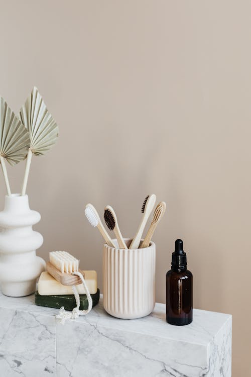 Free Collection of bamboo toothbrushes and organic natural soaps with wooden body brush arranged with recyclable glass bottle with natural oil and ceramic vase with artificial plant Stock Photo