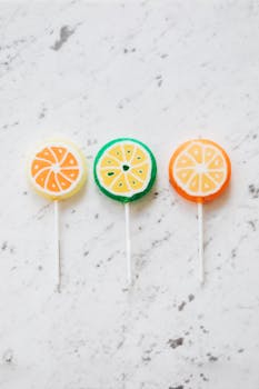 大理石表面上排列着明亮而诱人的柑橘主题棒棒糖