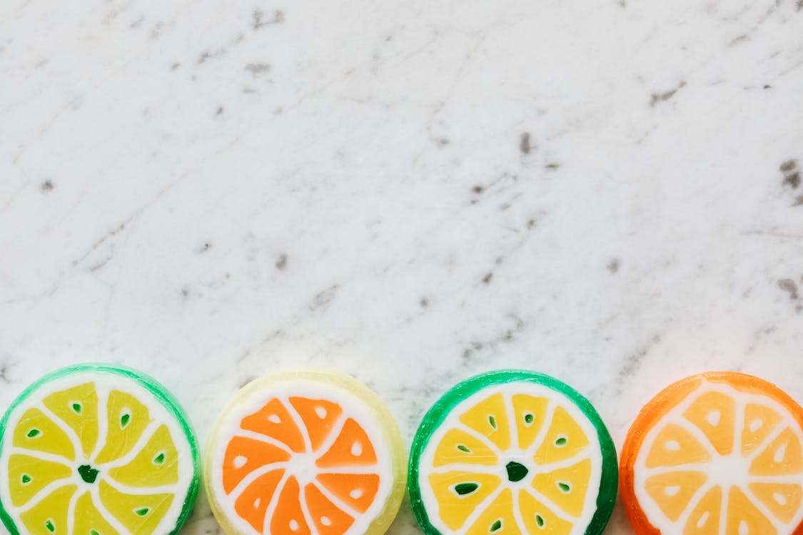 Top view of round shaped bright candies made in form of citrus fruits with wavy lines and small spots on dense surface