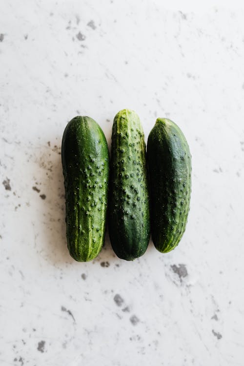3 Green Cucumbers on White Surface
