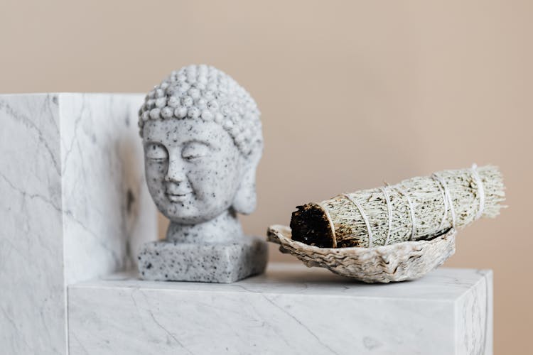 Bust Of Buddha And Dry Sage Bundle On Marble Surface