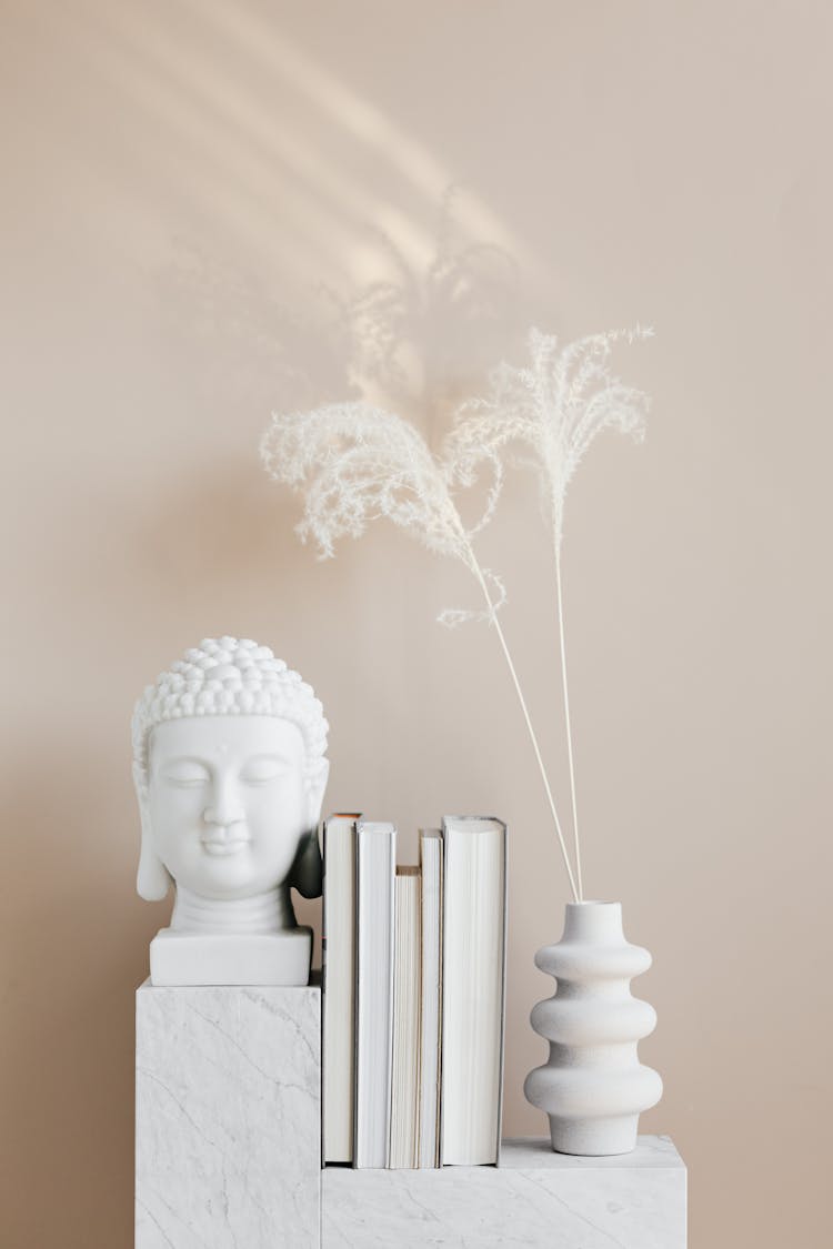 Vase With Dried Herbs Arranged With Buddha Bust And Books