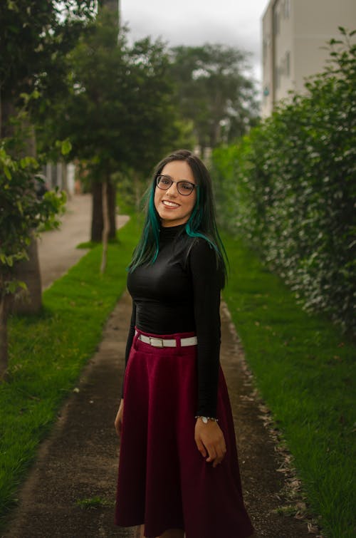 Woman in Black Long Sleeve Shirt and Red Skirt Standing on Pathway