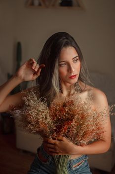 一名女子手持干花，在室内摆出姿势，画面捕捉到一种温暖而亲密的情绪