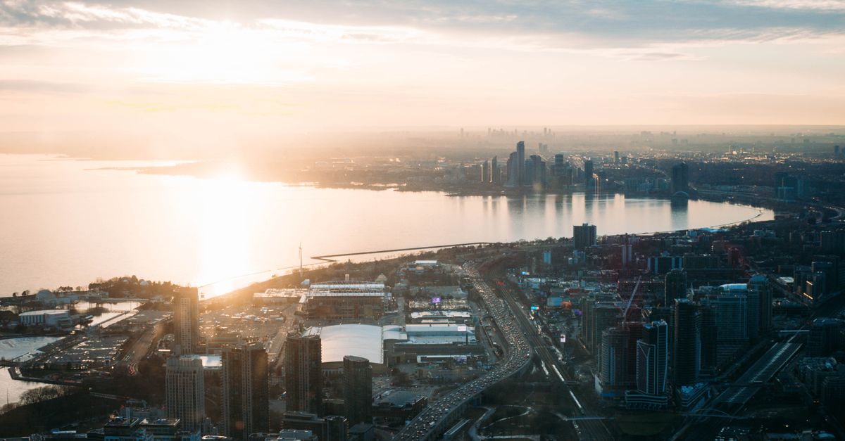 Breathtaking aerial view of Toronto's skyline during sunrise, highlighting Lake Ontario and urban architecture.