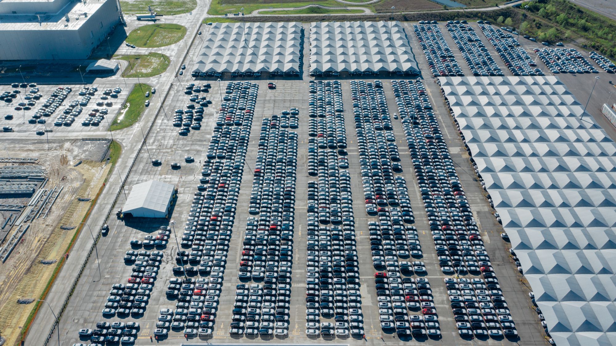 Aerial view of a large automotive plant lot with hundreds of finished vehicles best illustrates North American auto…