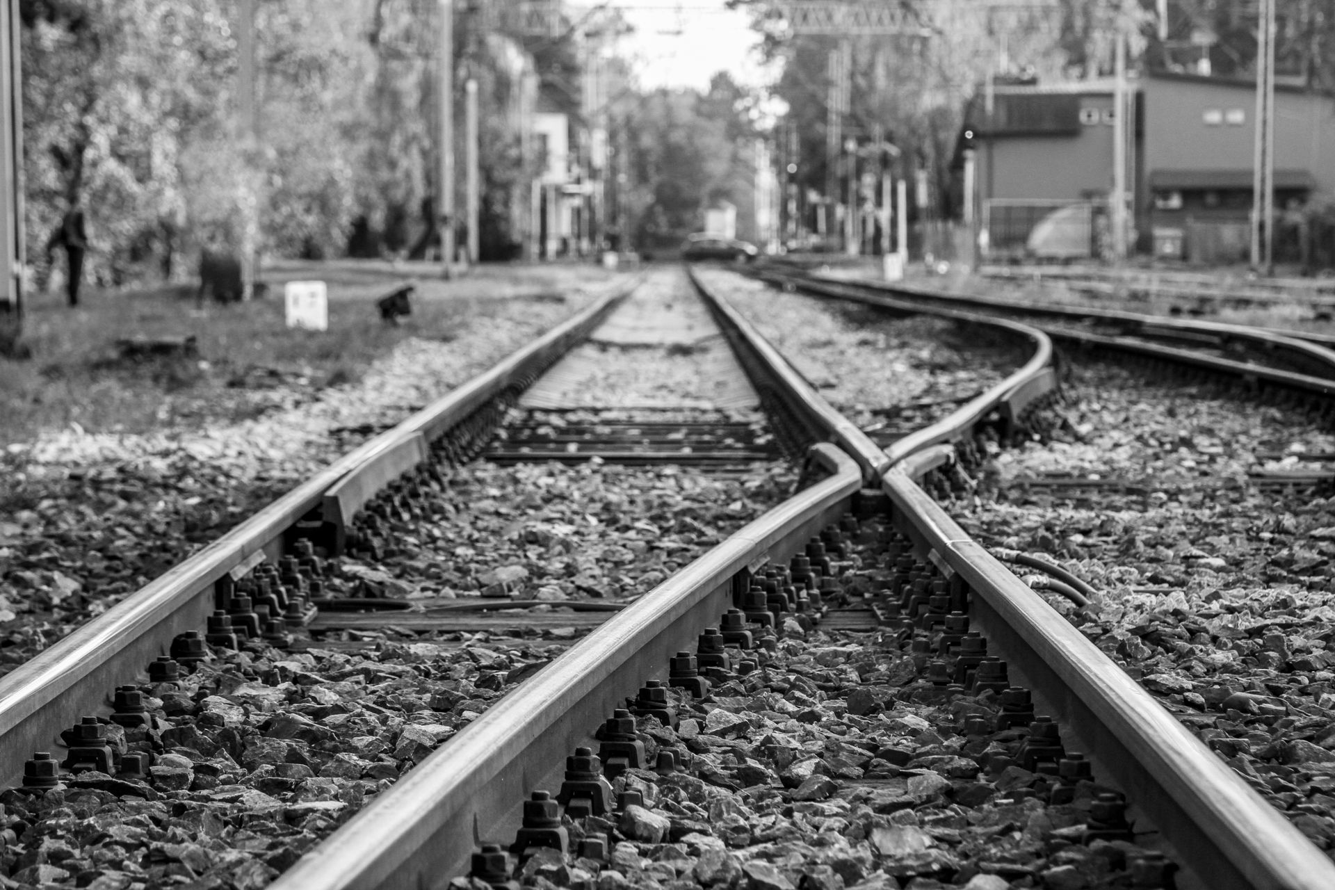 Black and white image of railway tracks converging at a station, symbolizing travel and journeys.
