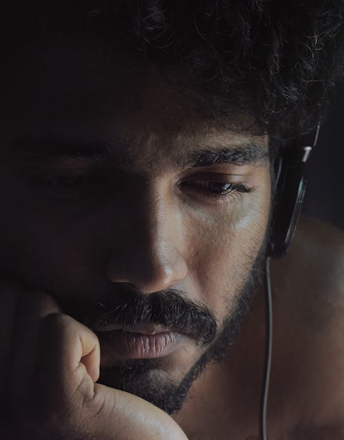 Close-Up Photo of Man Looking Sad While Wearing Black Headphones