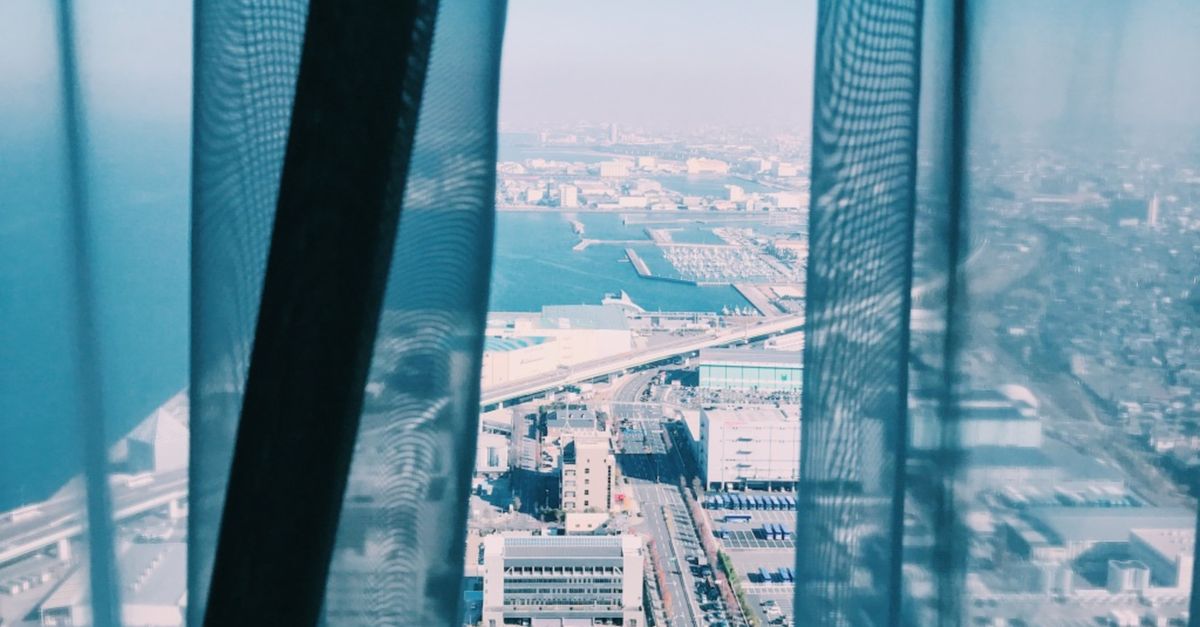 Breathtaking cityscape of Osaka with a stunning ocean view through a hotel window.