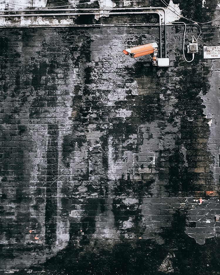 CCTV Camera Hanging In Grungy Weathered Wall On Street