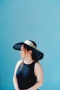 Woman Wearing a Round Hat on the Background of a Blue Wall