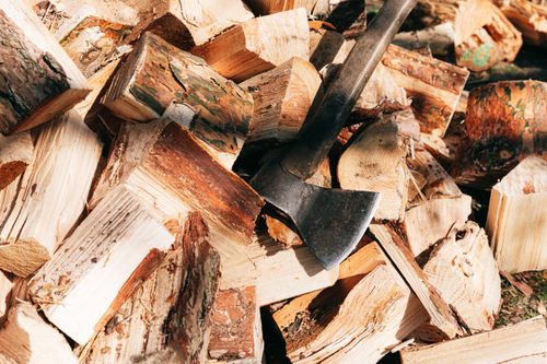 Free Old rustic axe with wooden handle and sharp cutting point placed on firewoods in forest on sunny summer day Stock Photo