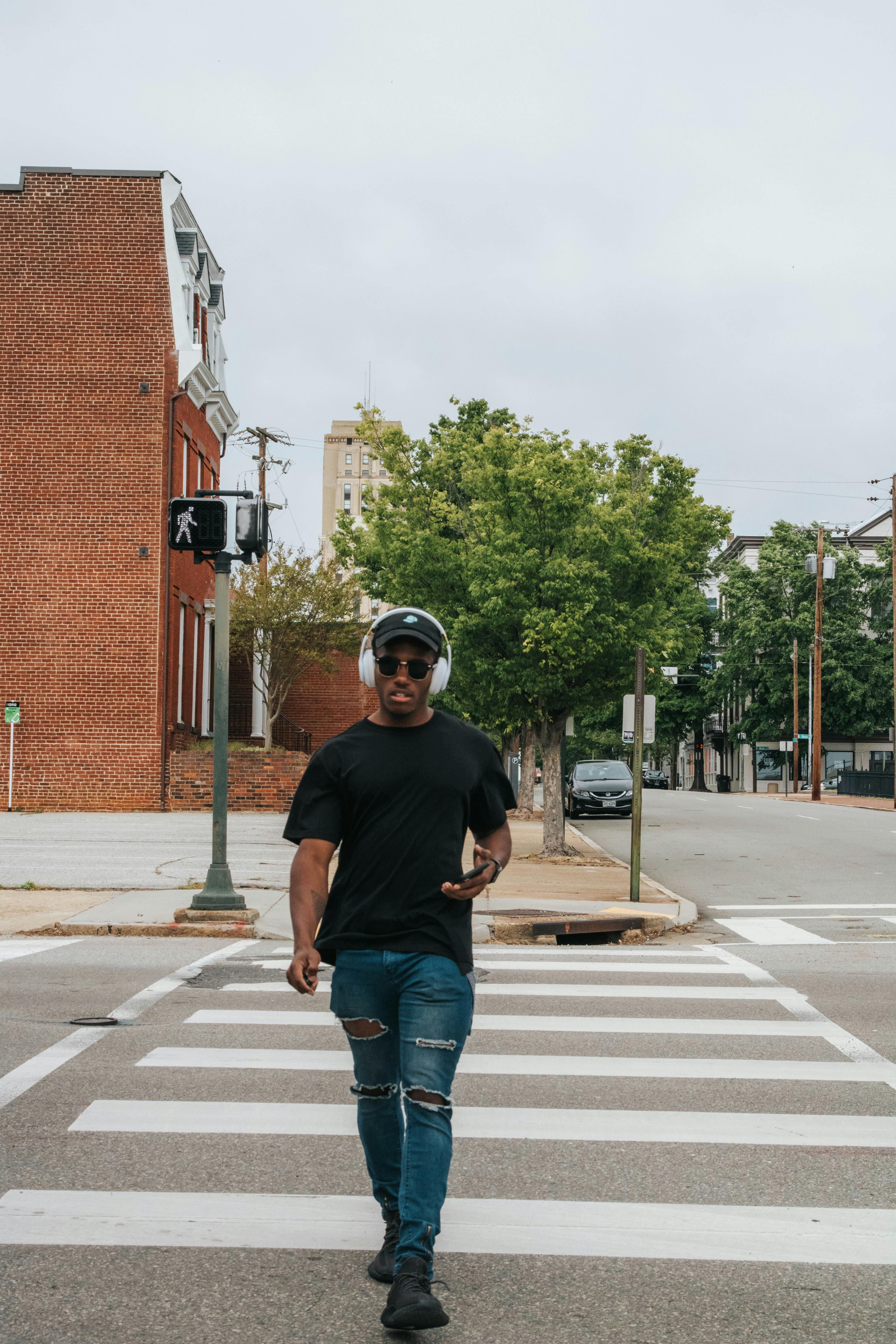 man in black crew neck t shirt and blue denim jeans crossing the street